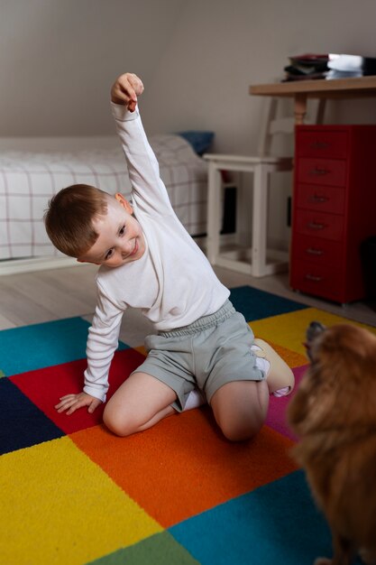 Foto niño de tiro completo jugando con perro en el interior