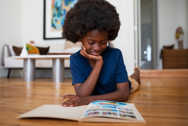 Foto niño de tiro completo leyendo cómics en casa