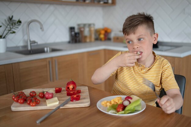 Niño de tiro medio comiendo vegetales