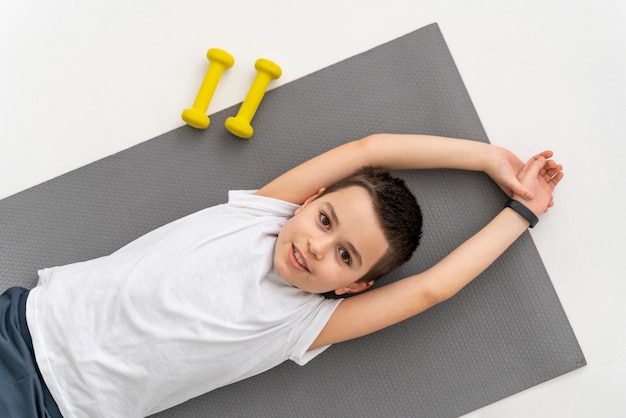 Niño de tiro medio en estera de yoga