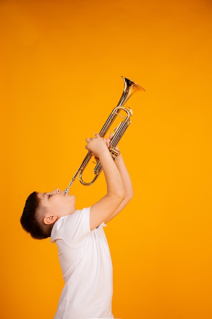 Foto un niño toca la trompeta. hermoso muchacho adolescente toca trompeta instrumento musical