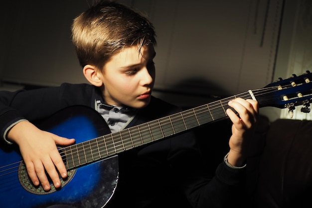 Foto un niño tocando una guitarra en un cuarto oscuro