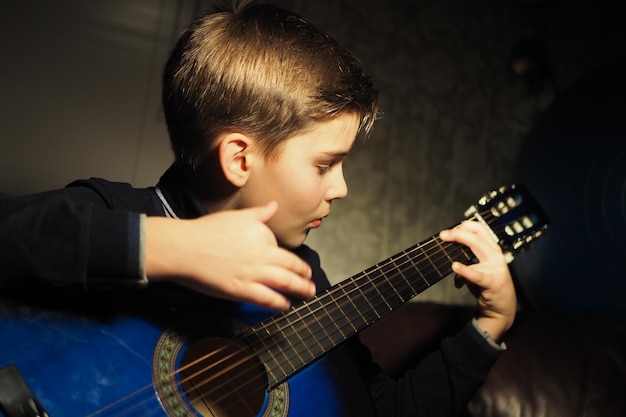 Foto un niño tocando una guitarra en un cuarto oscuro