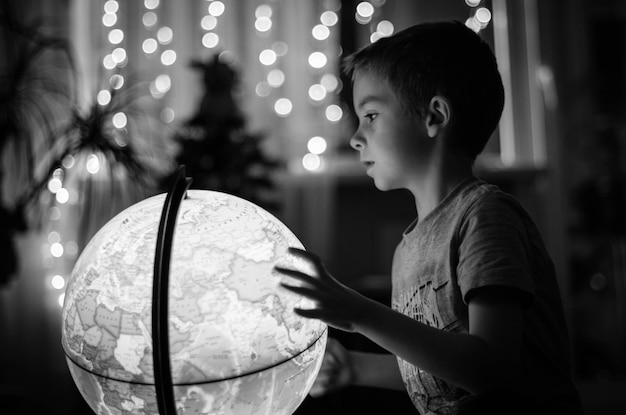 Niño tocando el mapa del mundo por la noche