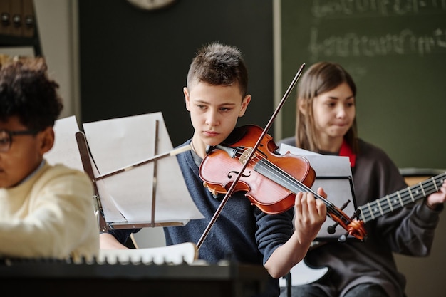 Niño tocando el violín en la orquesta de la escuela