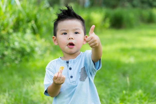 Niño tomando su bocadillo con el pulgar hacia arriba