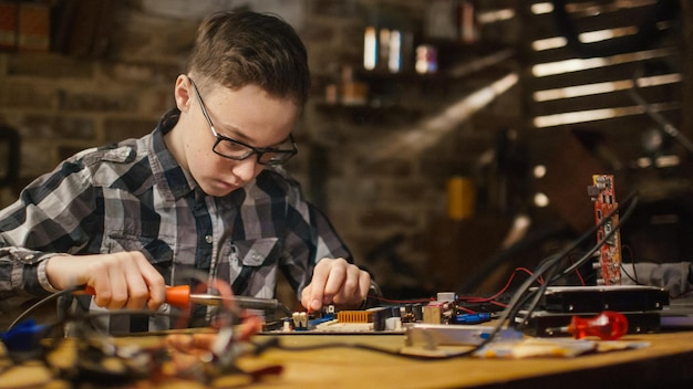 Un niño trabaja en una computadora con una placa de circuito.
