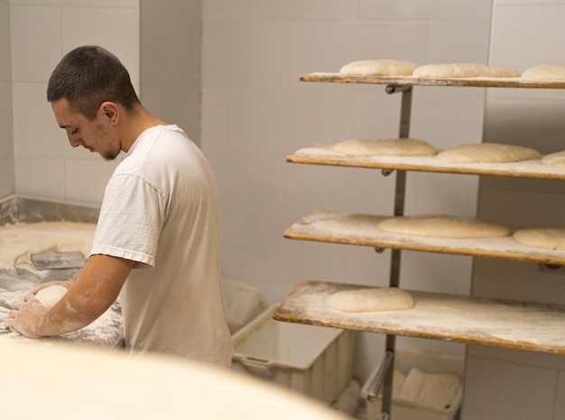 el niño trabaja de manera tradicional doblando el pan para dejarlo fermentar y luego hornearlo en su propia panadería