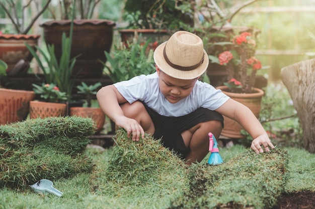Niño trabajando en jardinería césped en rollos Coloque el césped en el sitio de cultivo Zona del parque