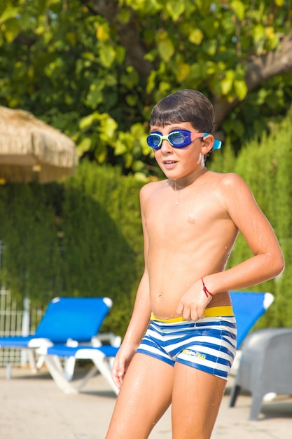 Un niño en traje de baño y gafas bañándose en la piscina en verano