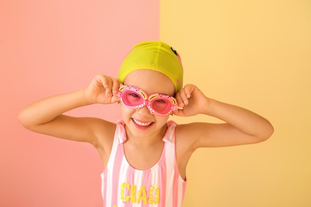 Niño en traje de baño y gafas y gorro de baño sonríe dulcemente mirando a la cámara