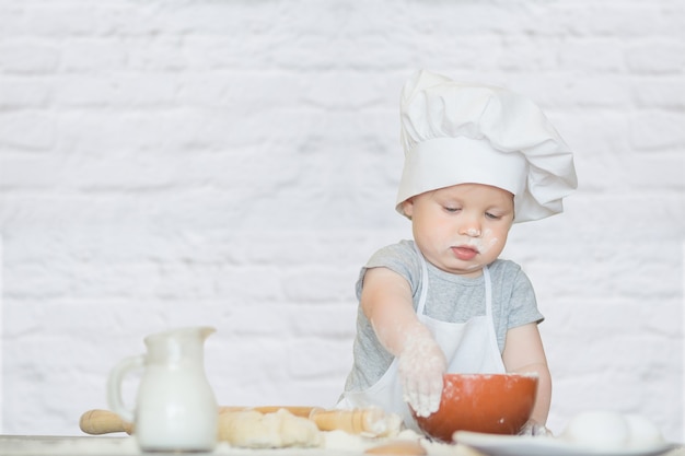 El niño con un traje de cocinero esculpe la masa.