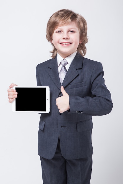 Niño con traje y corbata sosteniendo una tableta