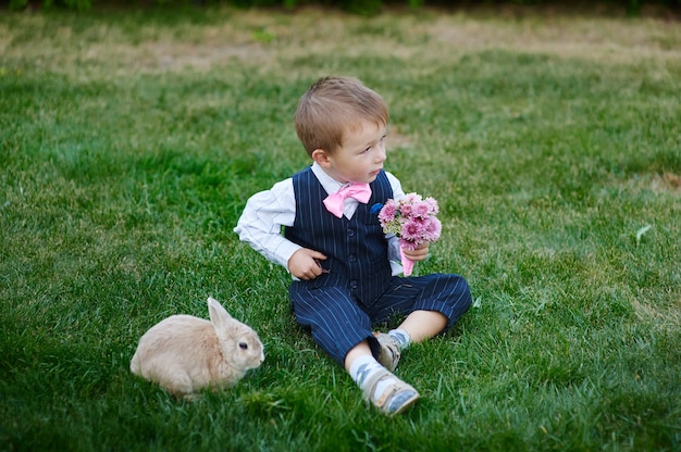 Niño en traje con un ramo de flores y un conejito