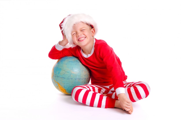 Niño con traje rojo de Santa y sombrero sonríe y sostiene un gran globo en sus manos