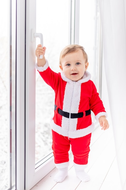 Niño en traje de Santa en el alféizar de la ventana, el concepto de año nuevo y Navidad