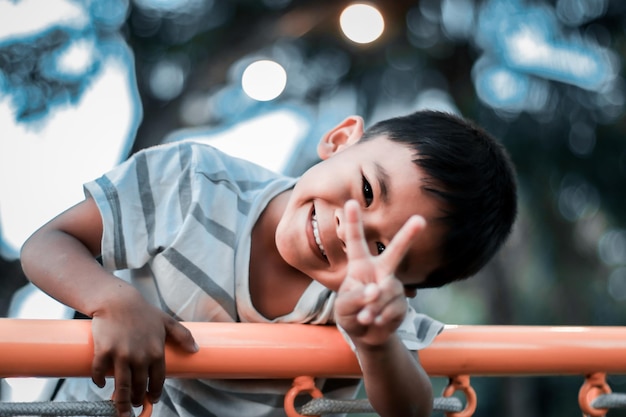 Un niño trepa por una cuadrícula alpina en un parque en un parque infantil en un caluroso día de verano parque infantil en un parque público entretenimiento y recreación para niños