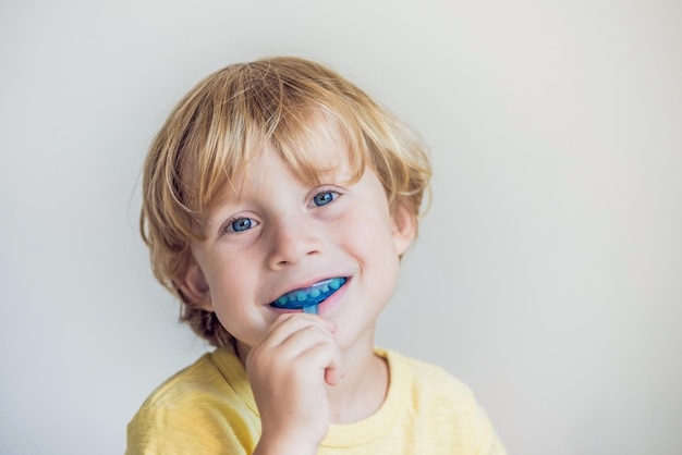 Un niño de tres años muestra un entrenador miofuncional para iluminar el hábito de respirar por la boca. Ayuda a igualar los dientes en crecimiento y corregir la mordida. Corrige la posición de la lengua.