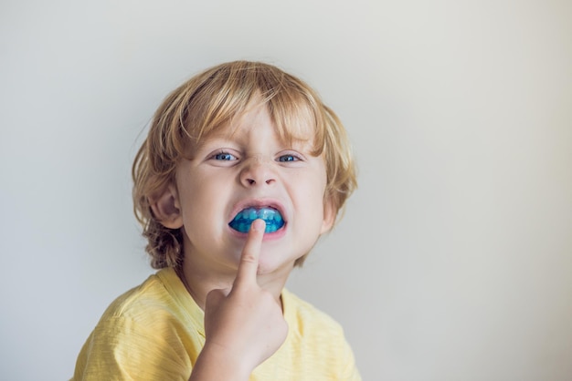 Un niño de tres años muestra un entrenador miofuncional para iluminar el hábito de respirar por la boca. Ayuda a igualar los dientes en crecimiento y corregir la mordida. Corrige la posición de la lengua.