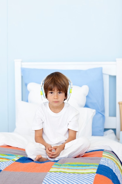 Niño triste escuchando música en la cama