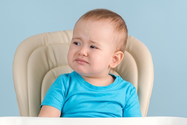 Niño triste llorando sentado en una silla de alimentación