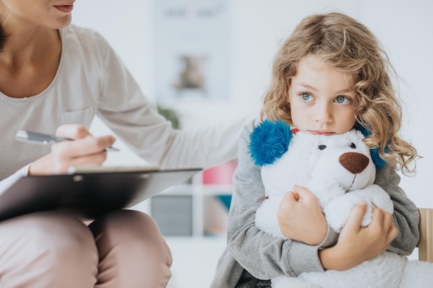 Foto niño triste con un oso de peluche