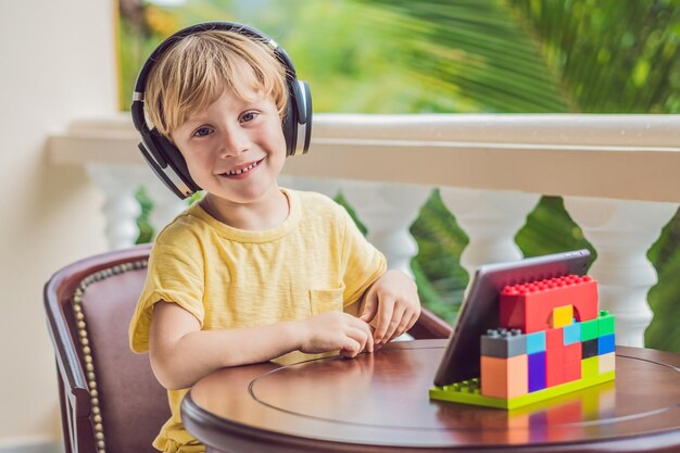 Niño en trópicos hablando con amigos y familiares en videollamadas usando una tableta y auriculares inalámbricos