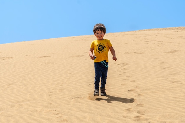 Niño turista sonriendo en las dunas de Maspalomas Gran Canaria Islas Canarias