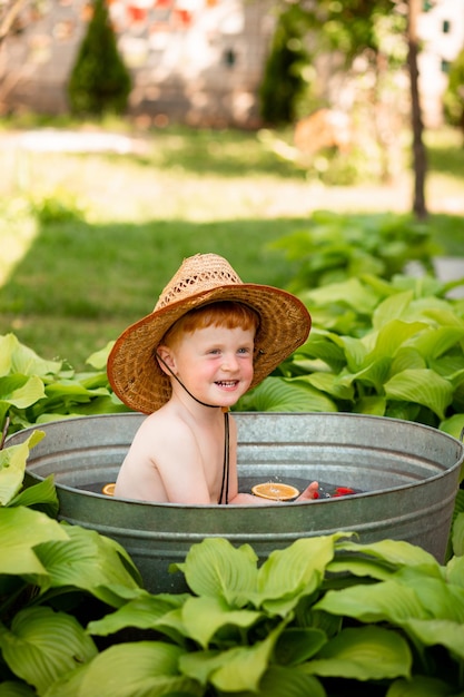 Un niño ucraniano pelirrojo con sombrero de abuelo nada en el agua en verano