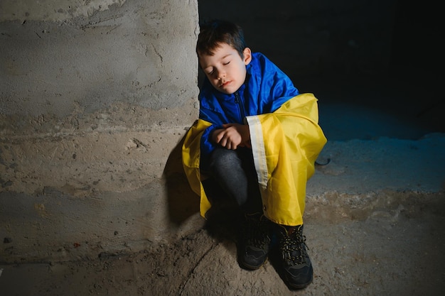 Un niño ucraniano triste envuelto en una bandera ucraniana que se esconde de los bombardeos en un refugio antiaéreo en la ciudad de Mariupol o Kiev La agresión de Rusia La guerra en Ucrania y 2022