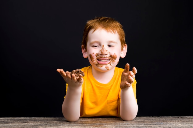 Niño untado en chocolate con leche después de mordisquear