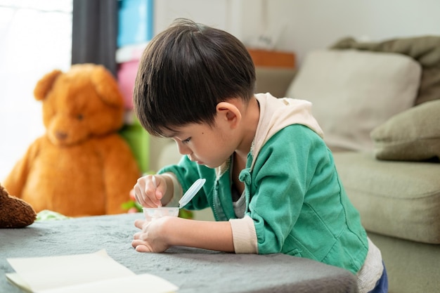 Un niño usa felizmente una cuchara para recoger yogur.