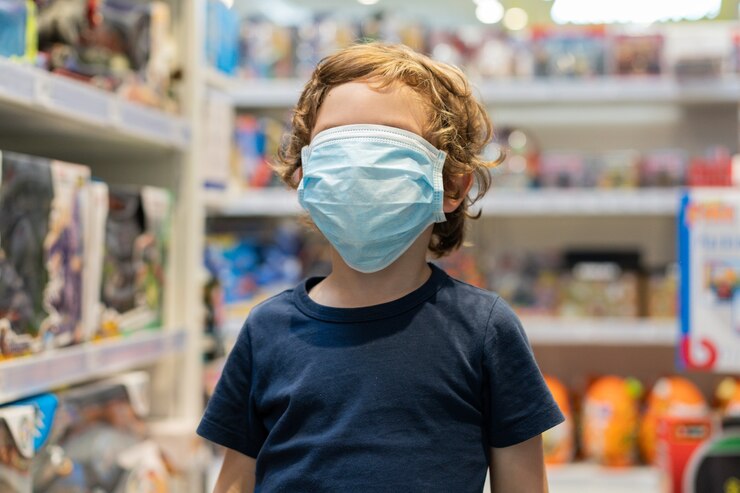 Foto el niño usa una máscara protectora en la tienda. seguridad, protección de la salud durante la cuarentena covid-19.