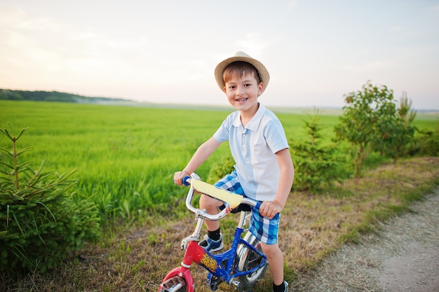 Niño usa sombrero en bicicleta, momentos de niños felices.