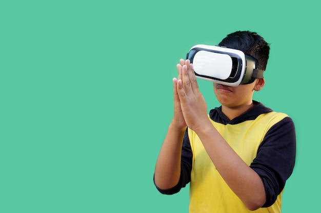 Niño usando auriculares de simulador de realidad virtual sobre fondo verde