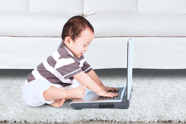 Niño usando una computadora portátil mientras está sentado en la alfombra en casa