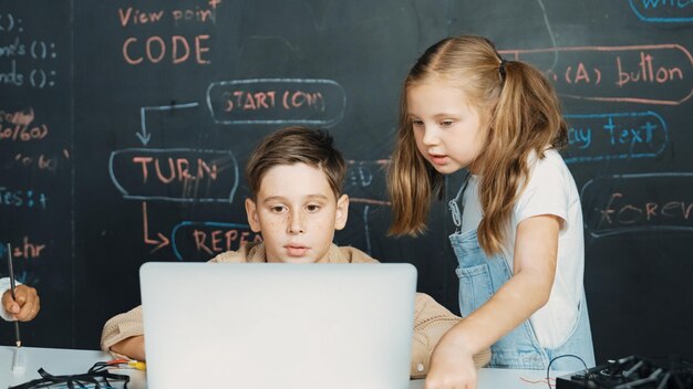 Niño usando una computadora portátil programando código de ingeniería y escribiendo programas Erudición