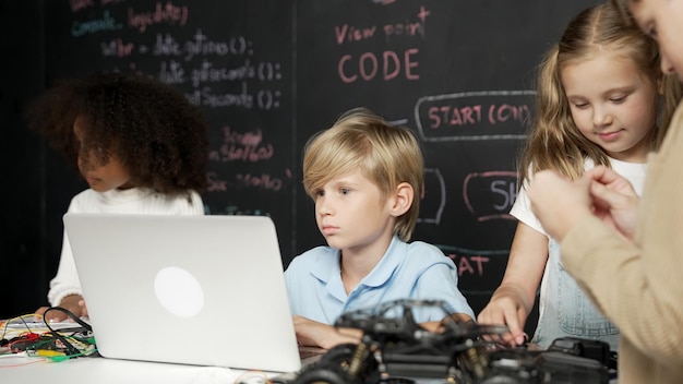 Niño usando una computadora portátil programando código de ingeniería y escribiendo programas Erudición