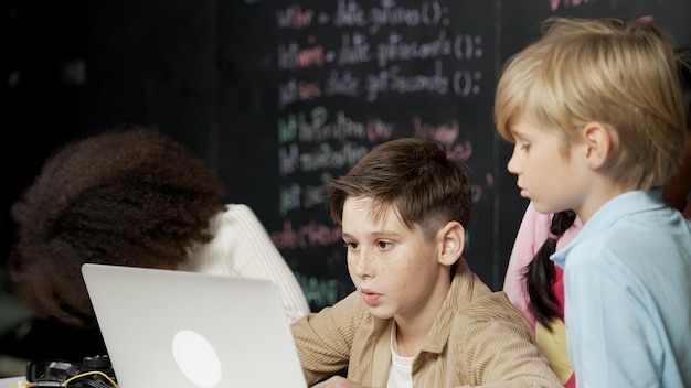 Niño usando una computadora portátil programando código de ingeniería y escribiendo programas Erudición
