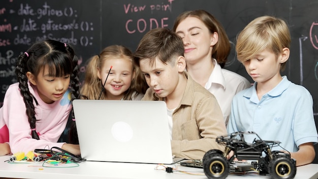 Niño usando una computadora portátil programando código de ingeniería y escribiendo programas Erudición