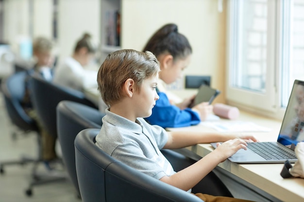 Niño usando portátil en la escuela en la clase de it para niños