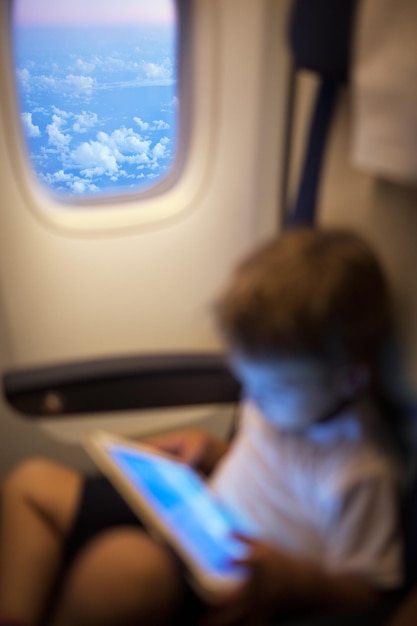 Foto niño usando una tableta digital mientras está sentado en un avión