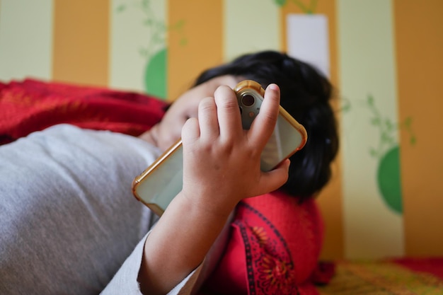 Niño usando un teléfono inteligente en la cama