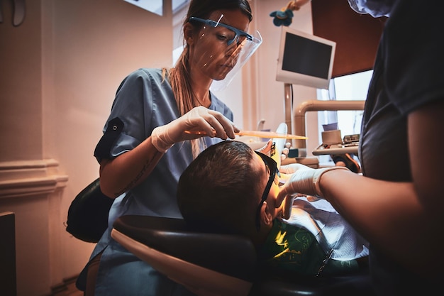 El niño valiente tiene una operación dental por parte del dentista y su asistente en el hospital.