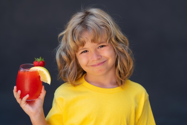 Niño con vaso de jugo niño beber cóctel de frutas bebida de verano refresco fondo gris