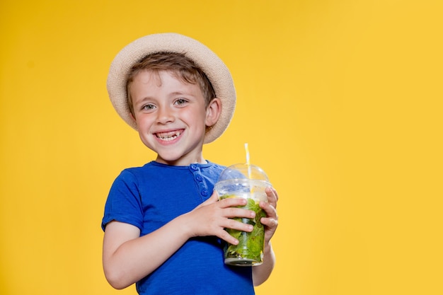 Niño con un vaso de plástico de limonada fresca