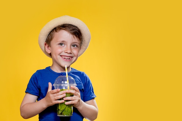 Niño con un vaso de plástico de limonada fresca