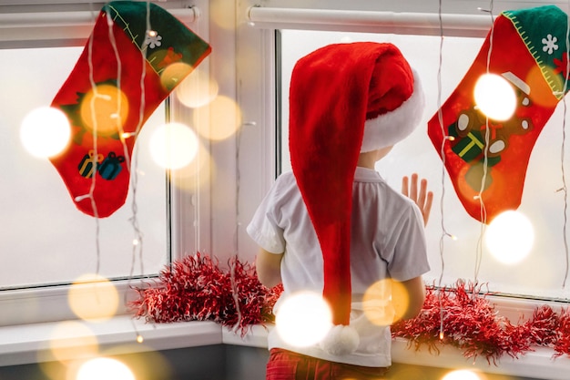 Un niño se para en la ventana durante la Navidad esperando a Nicolás con regalos