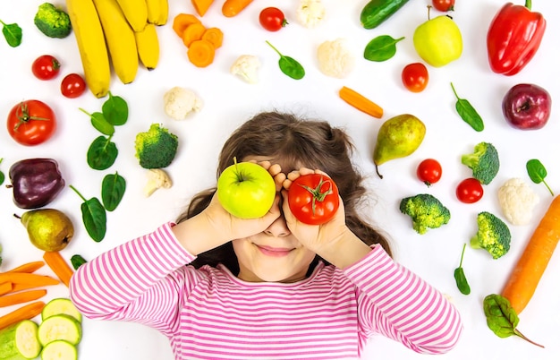 Foto un niño con verduras y frutas en sus manos.