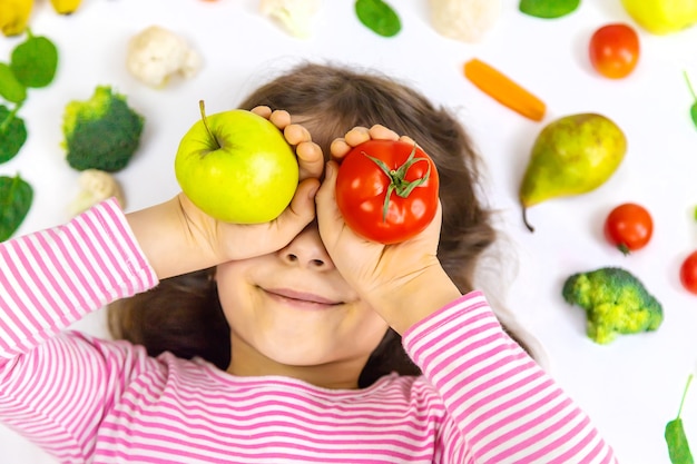 Foto un niño con verduras y frutas en sus manos.